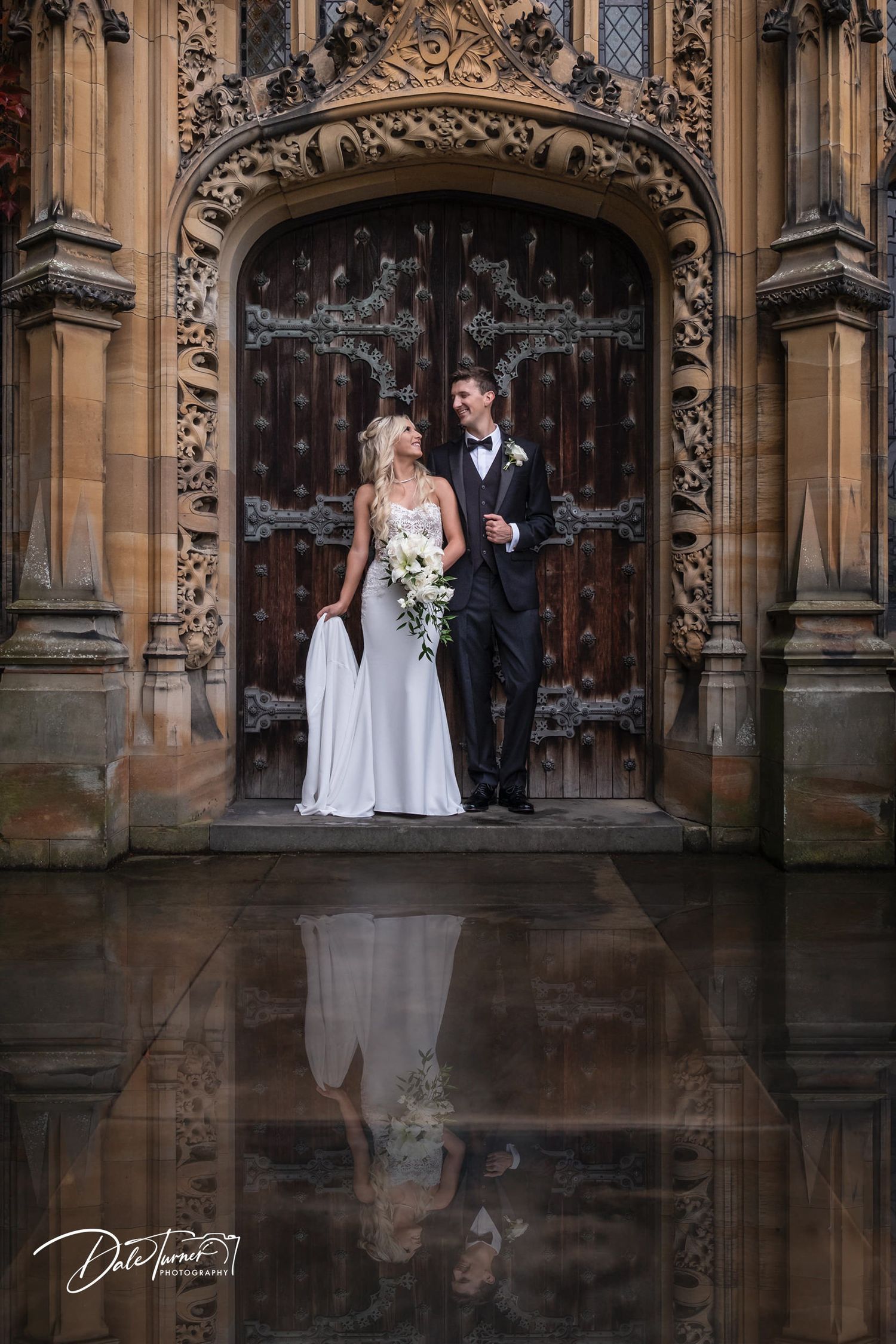 Gothic architectural entrance with ornate stone carvings and reflective wet ground.