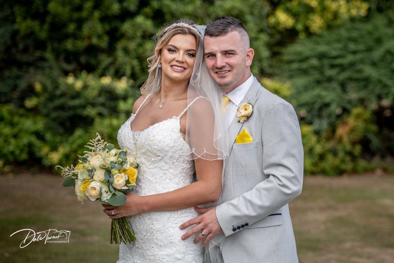 Newlywed couple sharing intimate moment outdoors with yellow floral accents.