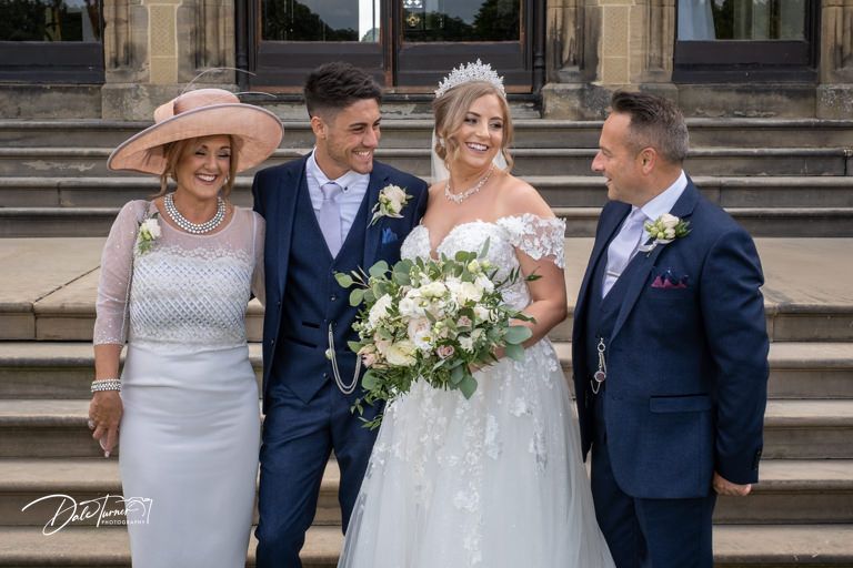 Wedding party in navy suits and lavender dresses poses together on stone steps.