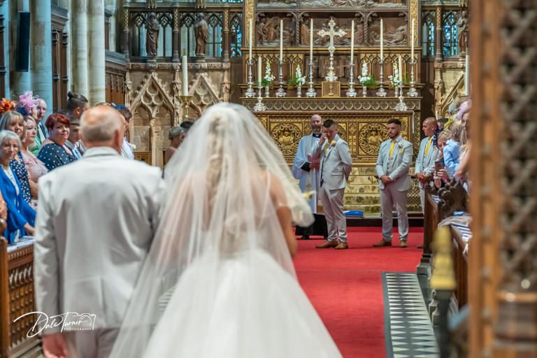 Wedding ceremony in a grand Gothic cathedral with ornate architectural details and red carpet aisle.