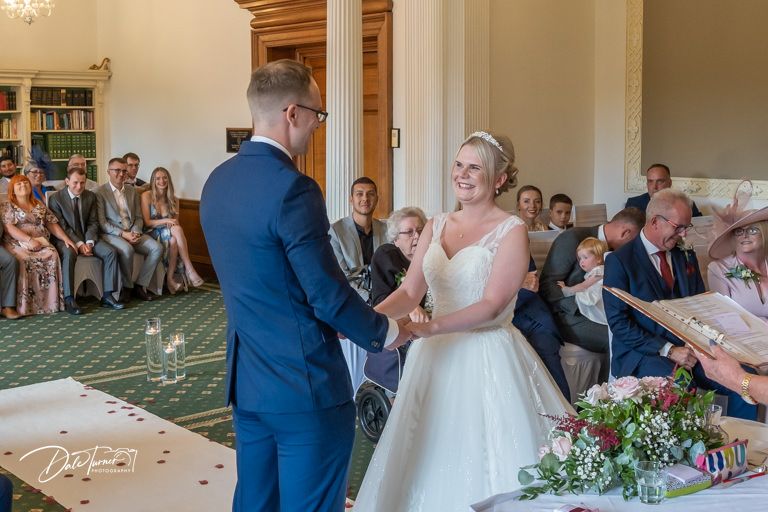 Wedding ceremony proceedings in an elegant indoor venue with chandelier and formal decor.