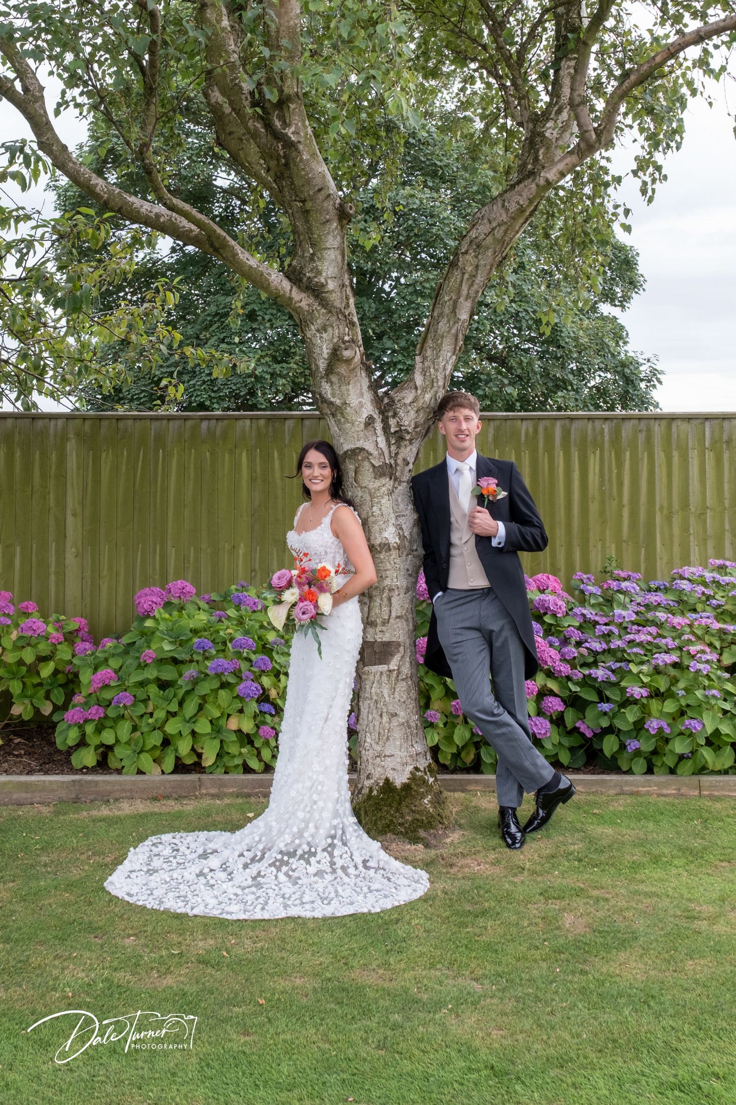 Garden wedding photos with blooming hydrangeas and tree creating natural frame.