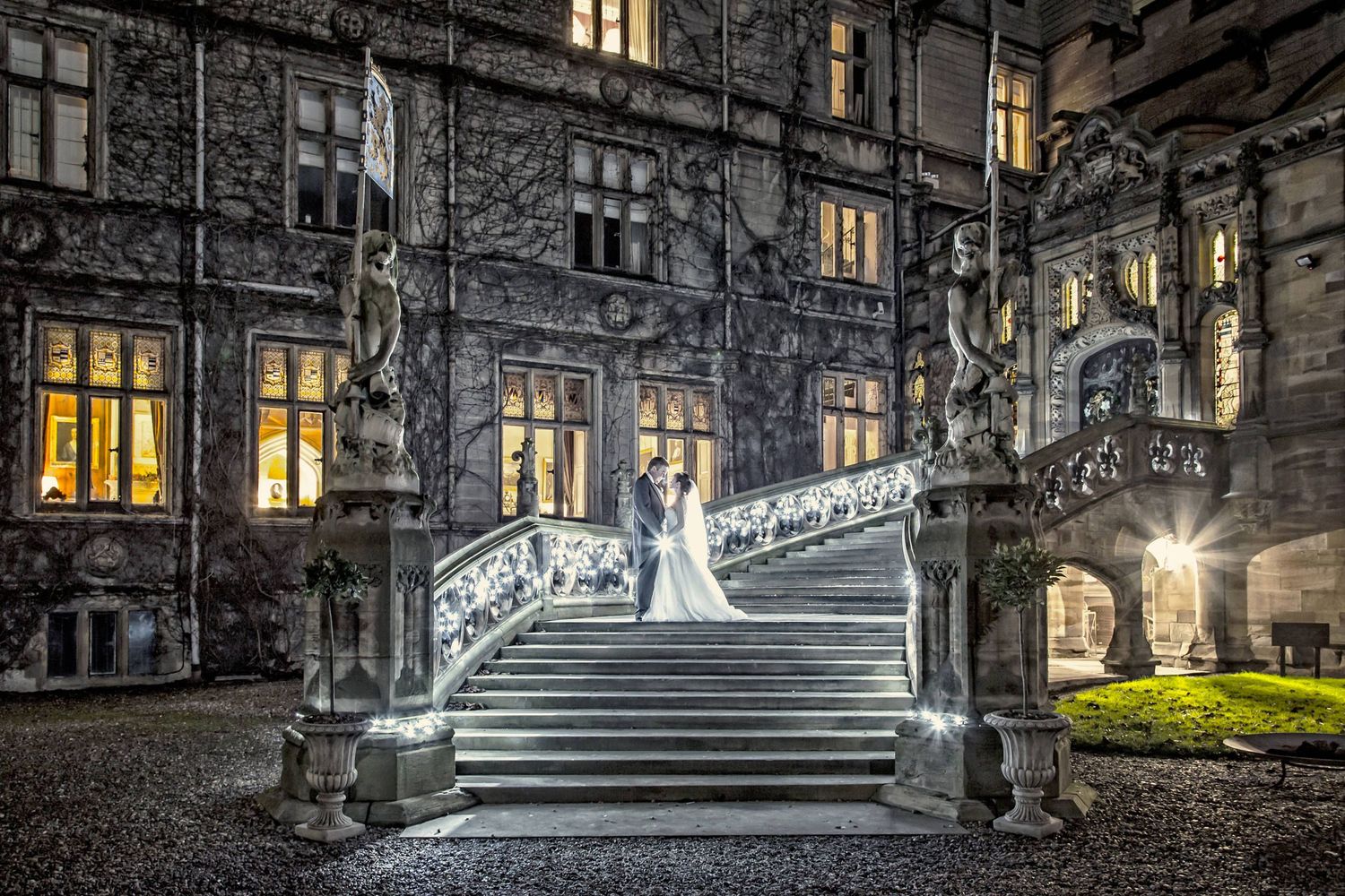 Illuminated gothic architecture at night with stairs and glowing windows creating dramatic atmosphere.