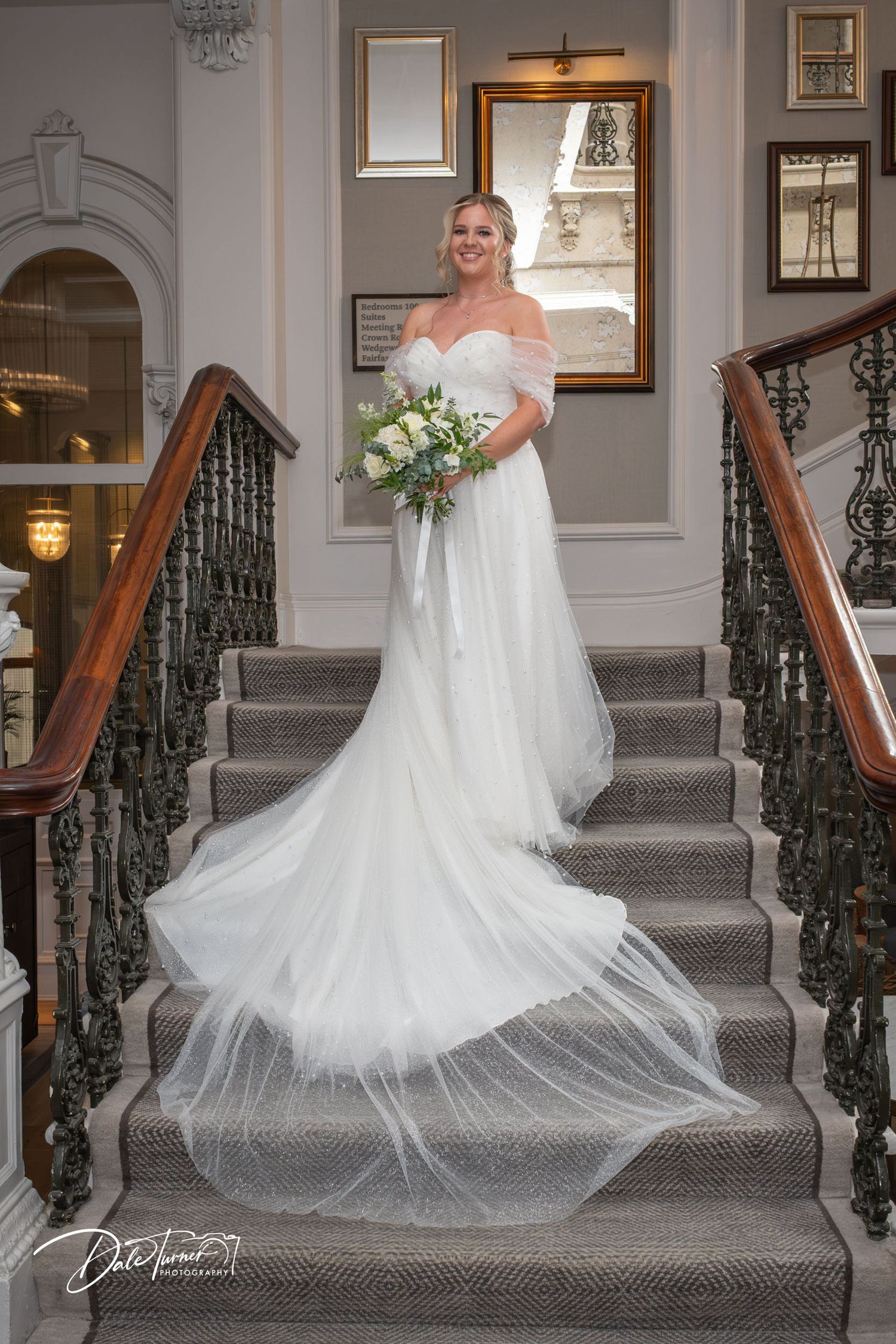 Elegant bridal portrait on a grand staircase with flowing white dress train.