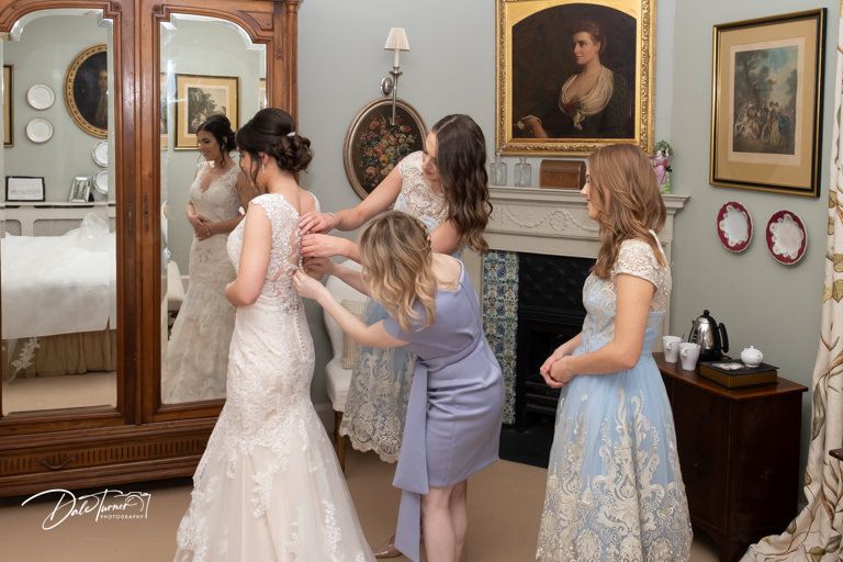 Wedding preparation scene in vintage room with ornate wooden furniture and portrait paintings.