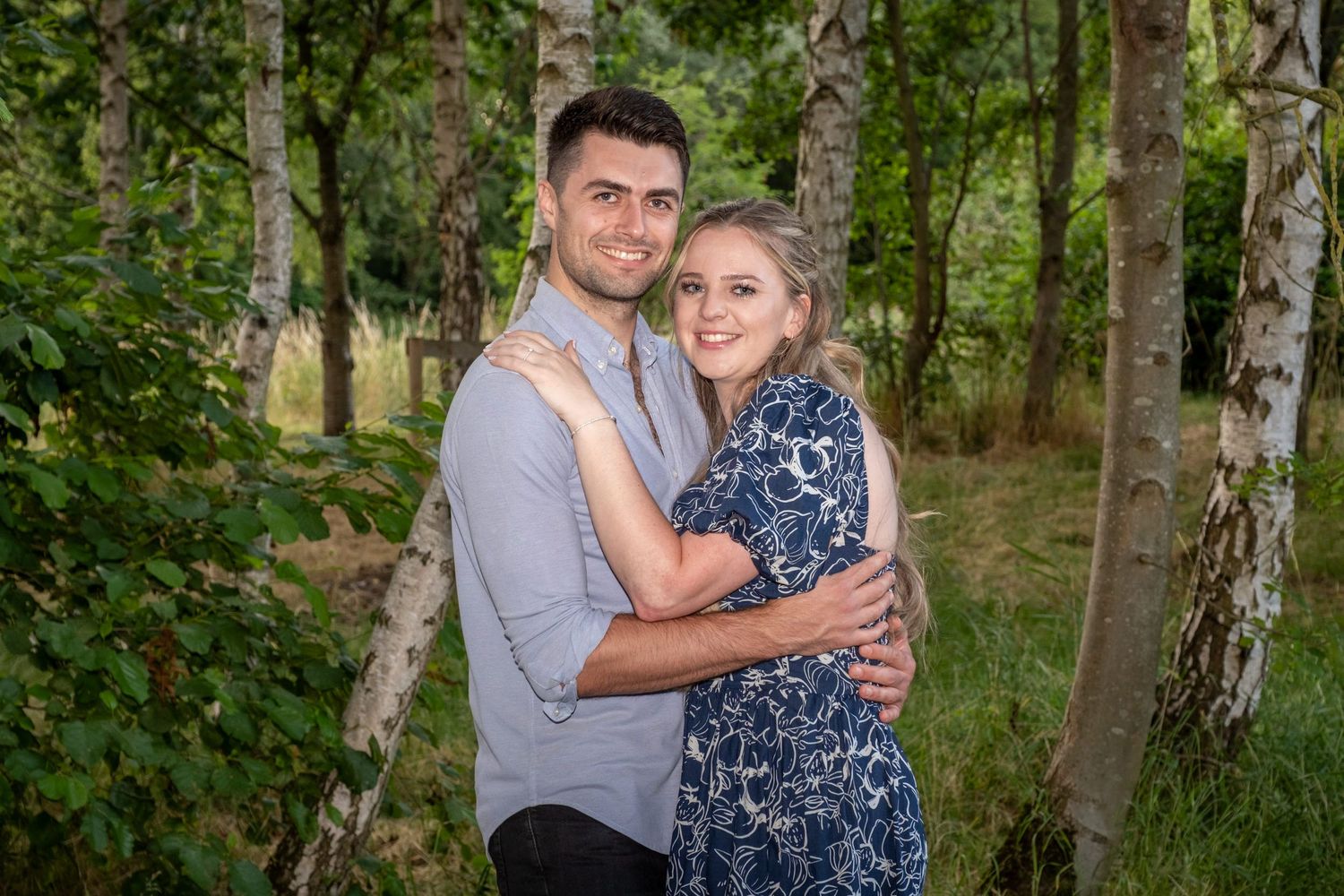 Casual engagement photos taken in a birch forest with natural lighting.