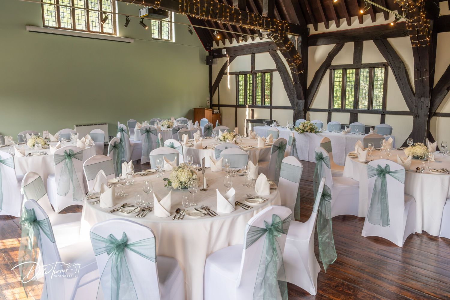 Wedding reception hall decorated with white chair covers and mint green accents.