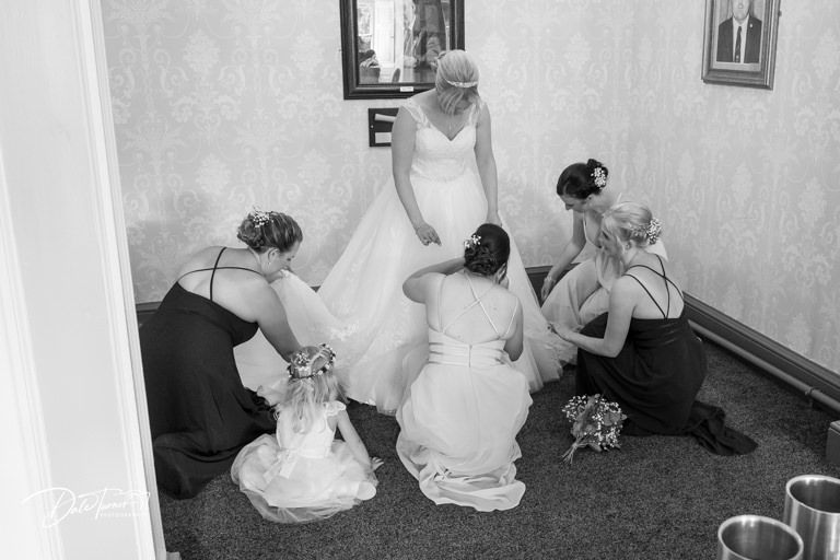Wedding party members sit together on a carpeted floor during preparations.