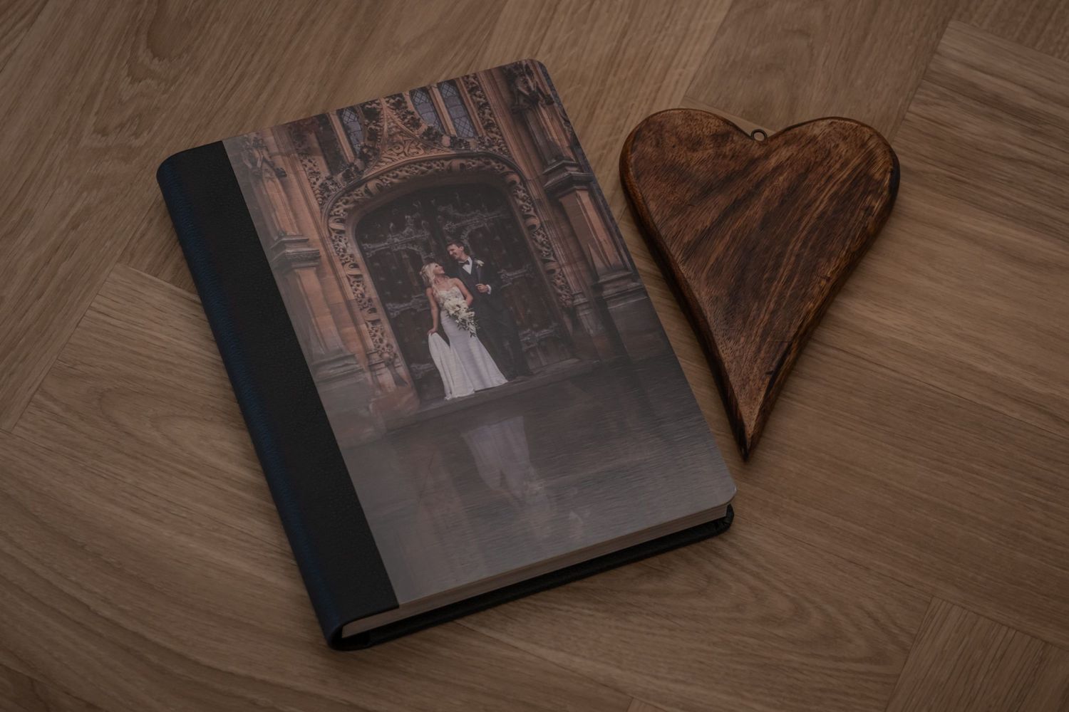 Wedding album layout with artistic black and white photographs on wooden background.