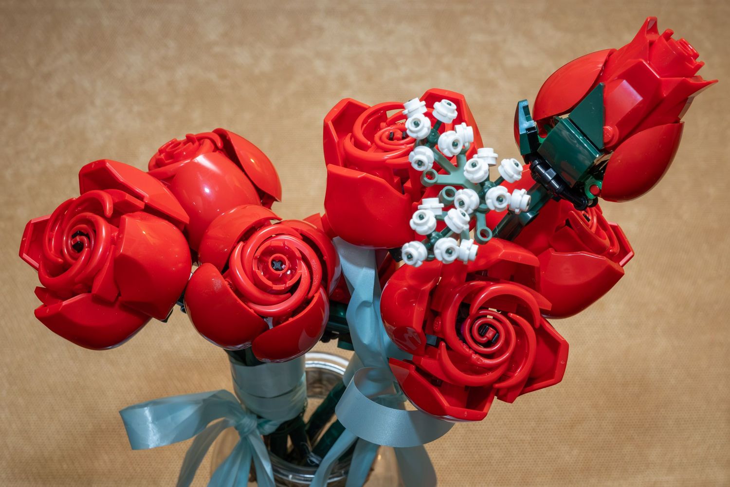 Red roses with blue ribbons arranged in a decorative wedding bouquet against a brown background.