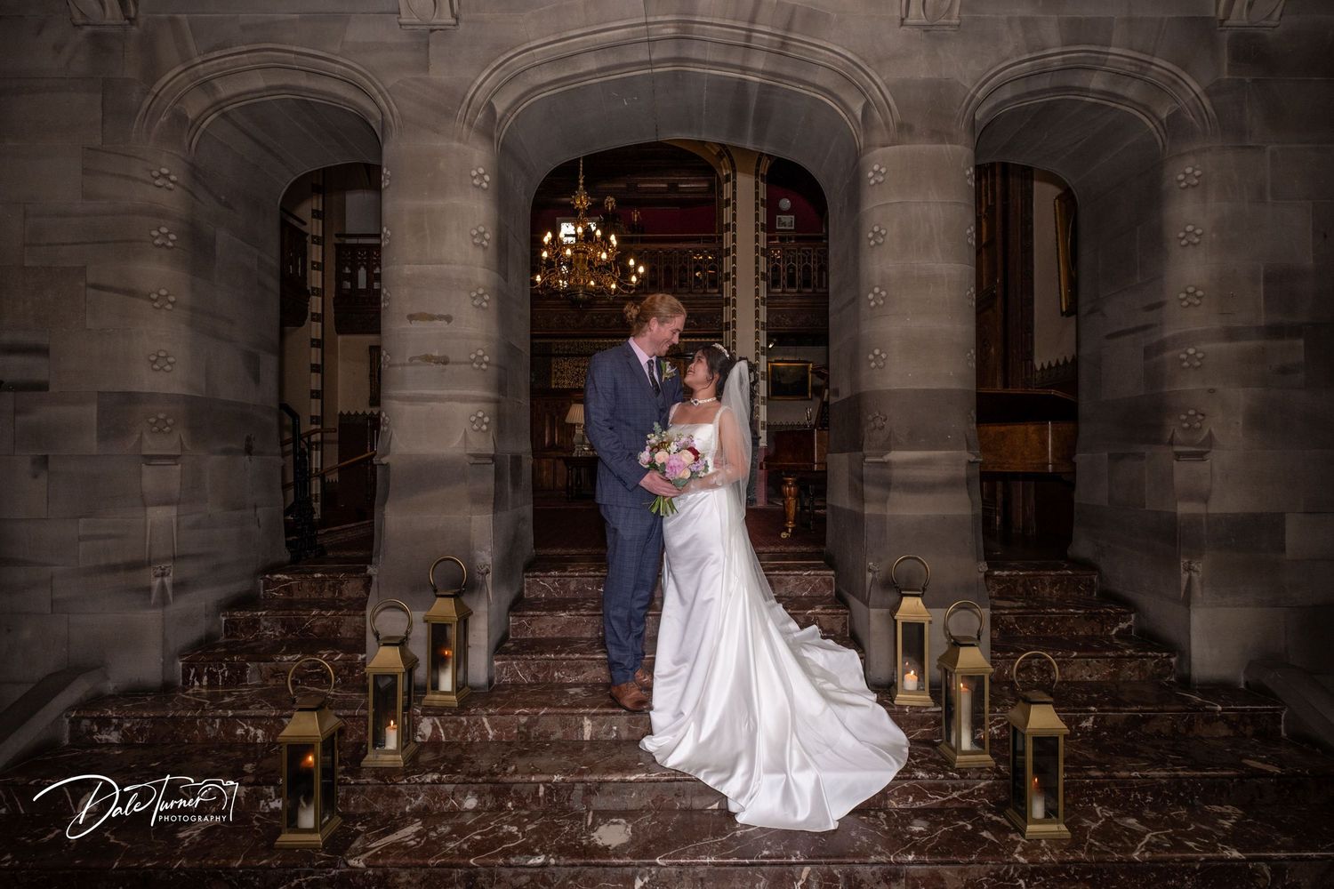 Wedding photography in a grand stone colonnade with dramatic lighting.