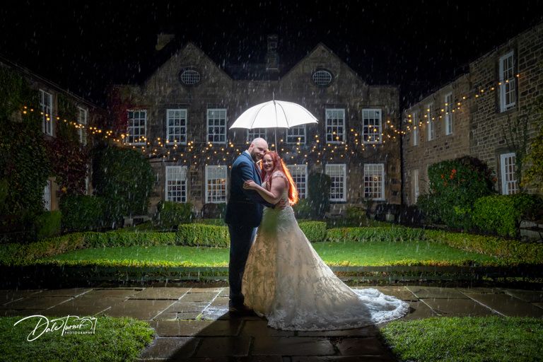 Romantic wedding portraits captured at dusk with a white umbrella against classic architecture.