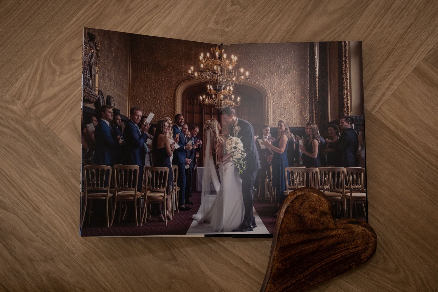 Open wedding photo album showing elegant reception venue photos with decorative lighting.