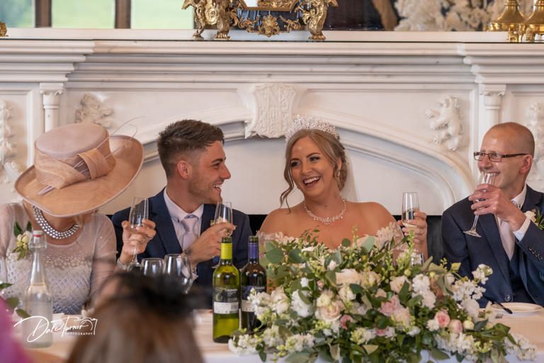 Elegant wedding reception with ornate decor and floral arrangements on dining tables.