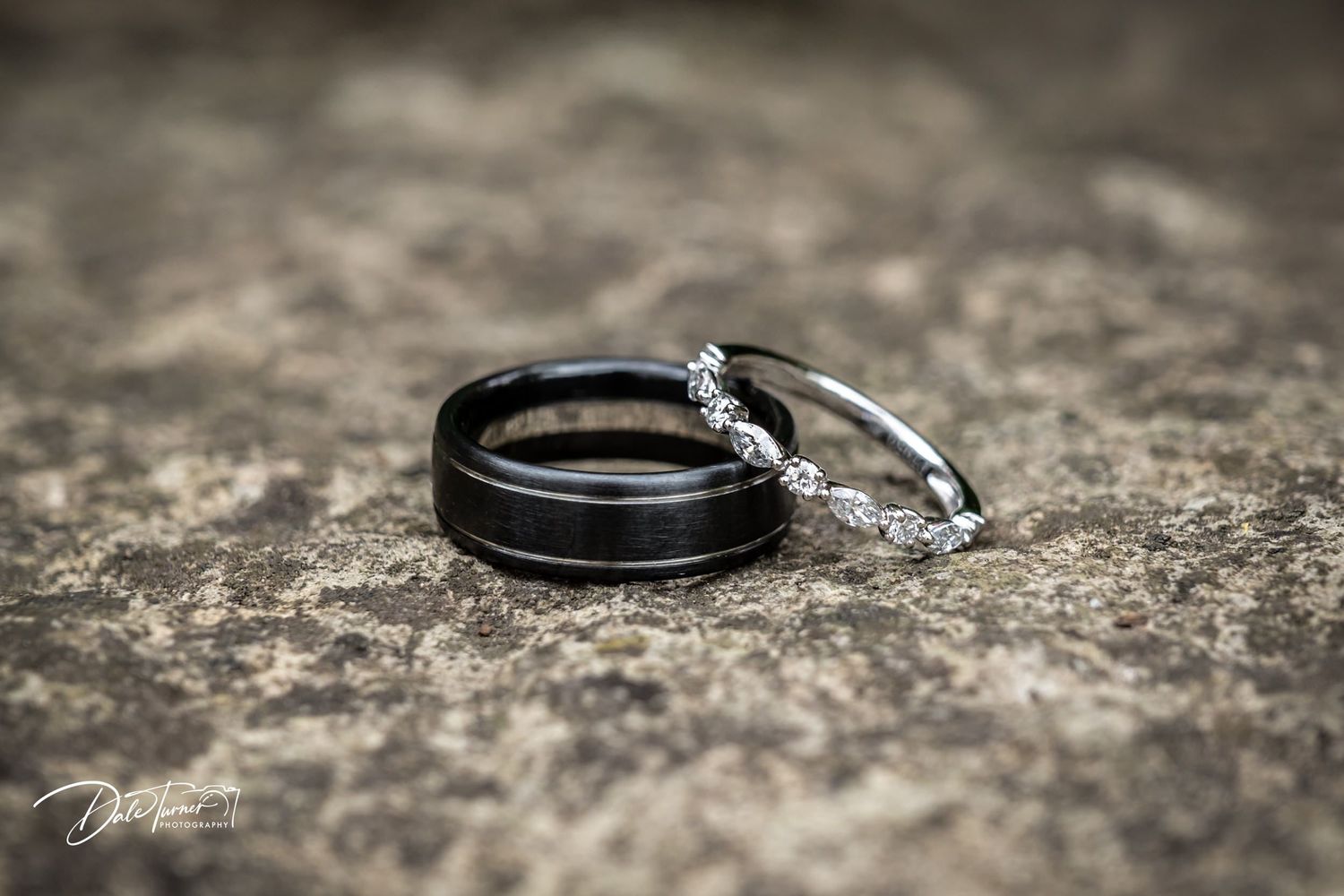 Close-up of wedding rings on textured stone surface with artistic lighting.