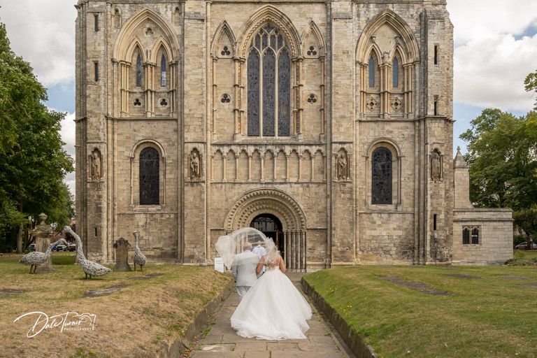 Gothic church exterior with detailed stonework and arched entrance on grassy hill.