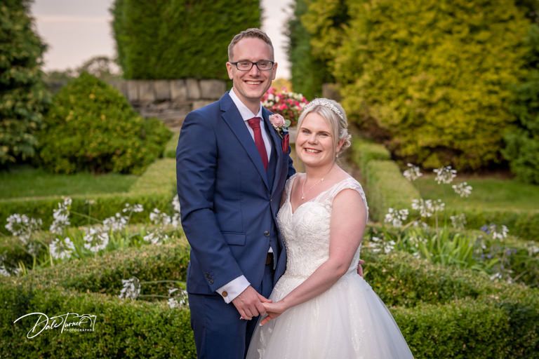 Wedding couple shares an intimate moment in a lush garden setting at sunset.