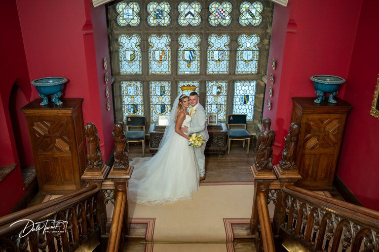 Church interior with stained glass windows and red walls during a wedding ceremony.