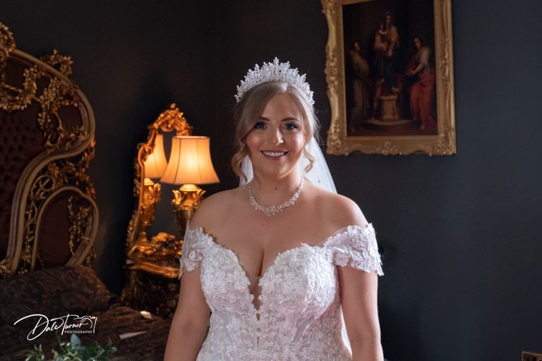 Bridal preparations in an ornate room with vintage decor and warm lighting.