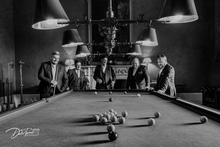 Dramatic black and white shot of a billiards table in low lighting.