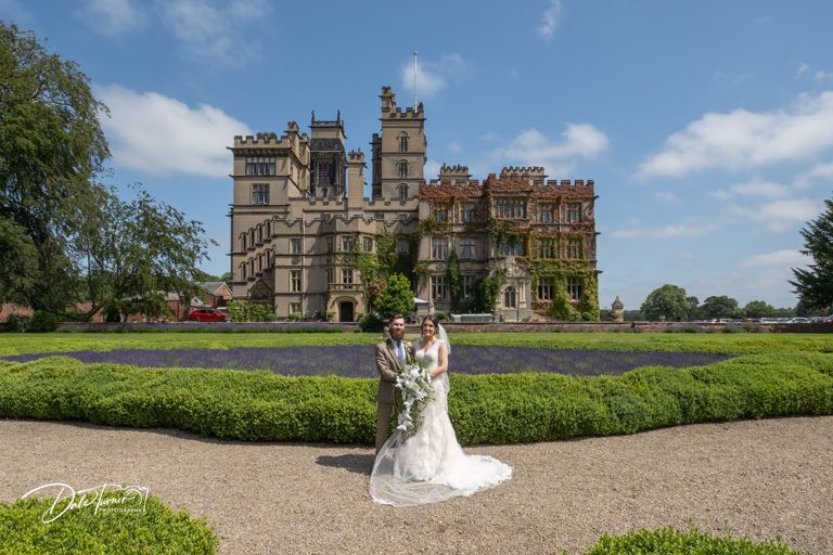 Scenic view of historic manor house with gravel driveway and landscaped grounds.