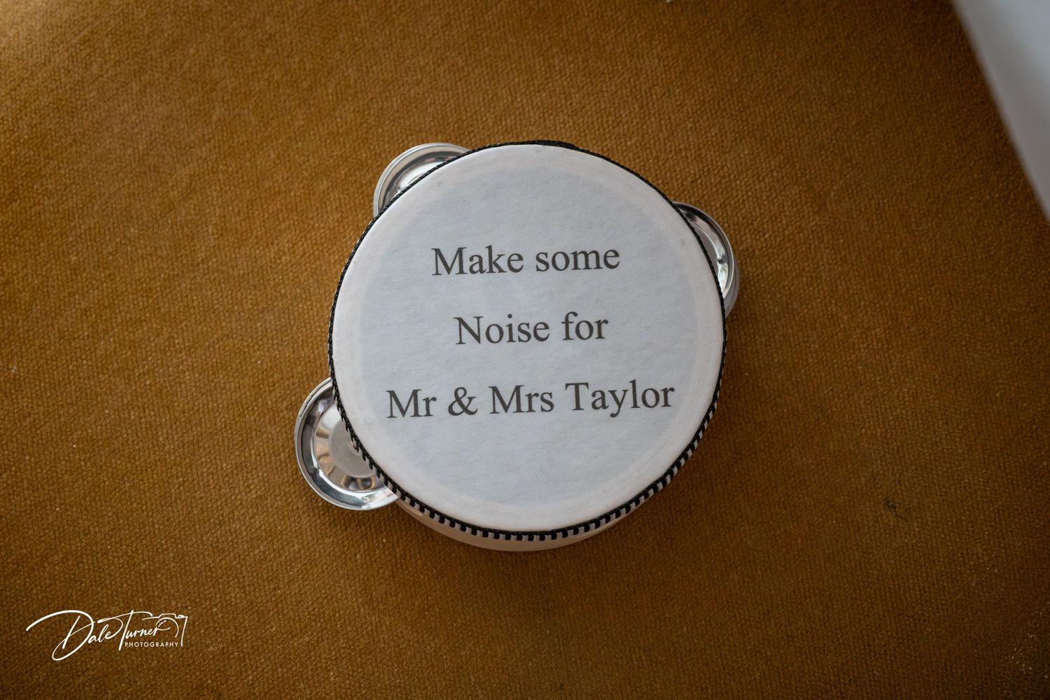 Engraved tambourine wedding favor reading Make Some Noise for Mr and Mrs Taylor on a golden background.