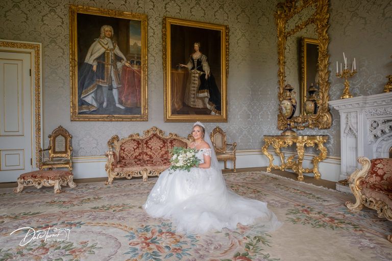 Elegant wedding party photo session in an ornate historic room with gilded frames and classical decor.
