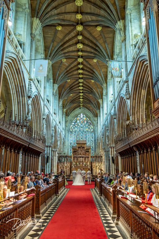 Majestic cathedral interior showing vaulted ceiling, wooden pews and red carpet aisle.