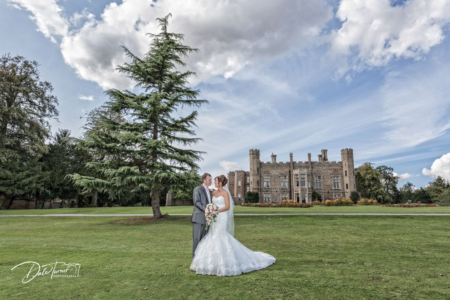 Expansive castle grounds with manicured lawn and historic architecture under blue summer sky.