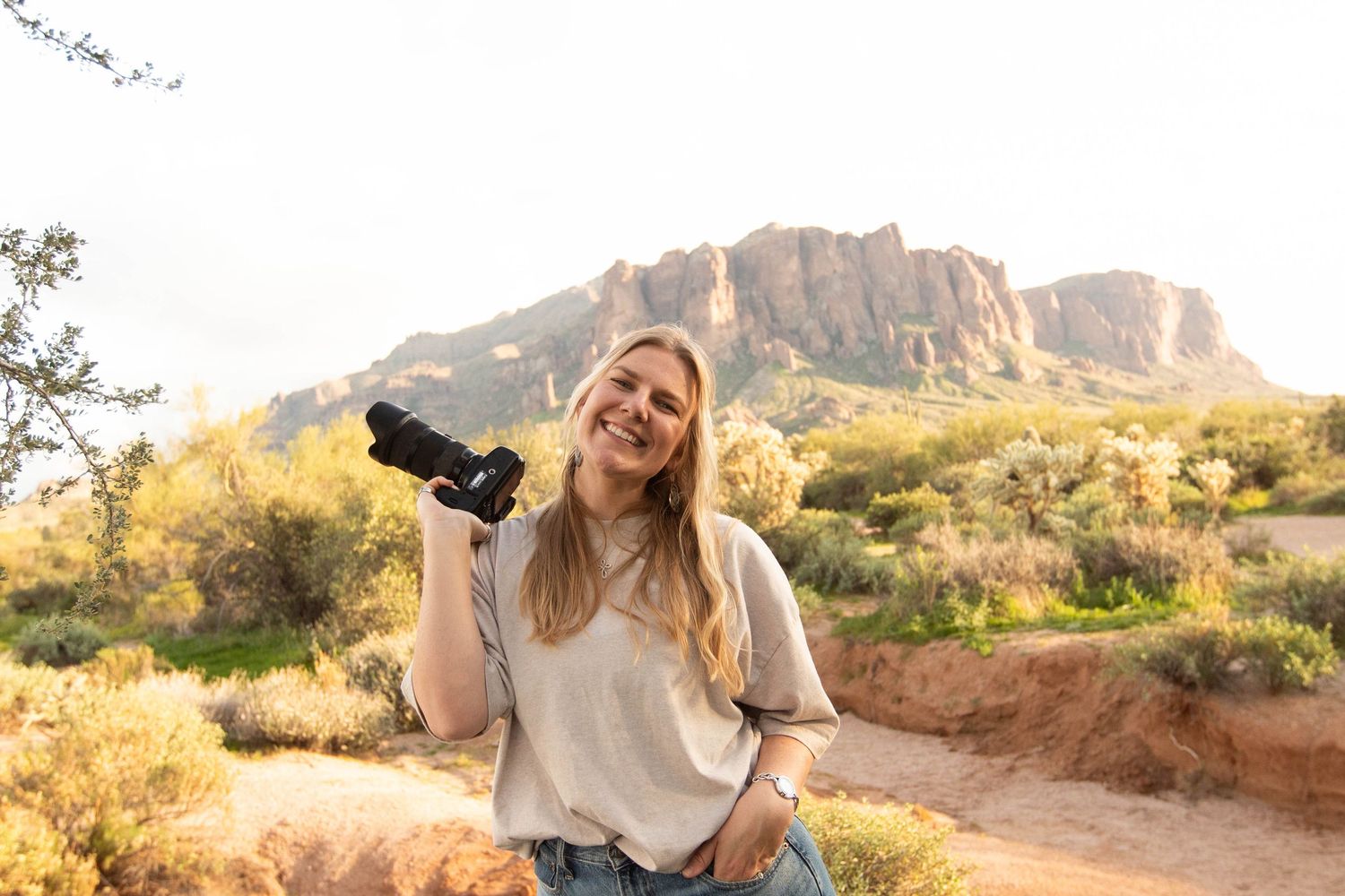 woman holding camera, smiling in the desert