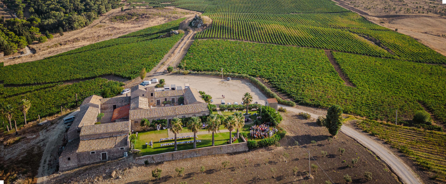 Aerial view of a rustic winery estate surrounded by lush green vineyards on rolling hills.