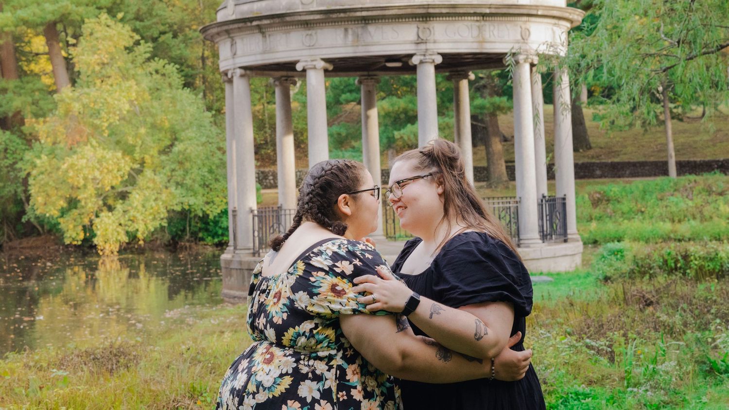 A couple dances together in a garden gazebo surrounded by lush greenery and autumn foliage.