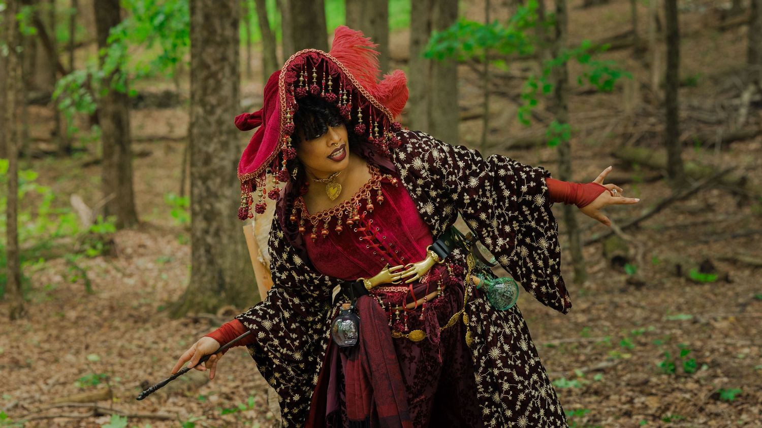 Woman in colorful traditional costume dancing gracefully in a forest setting.
