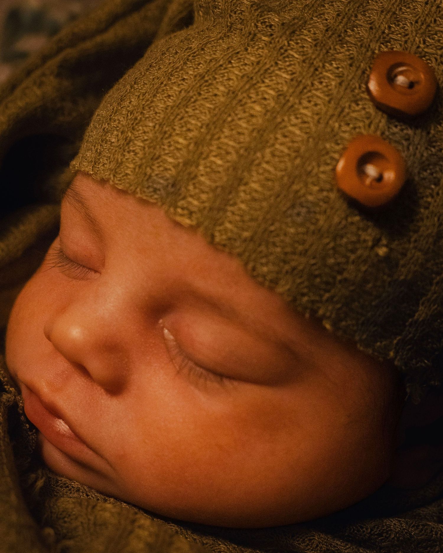 A close-up series of images showing a sleeping baby's face with soft lighting and textured brown fabric.