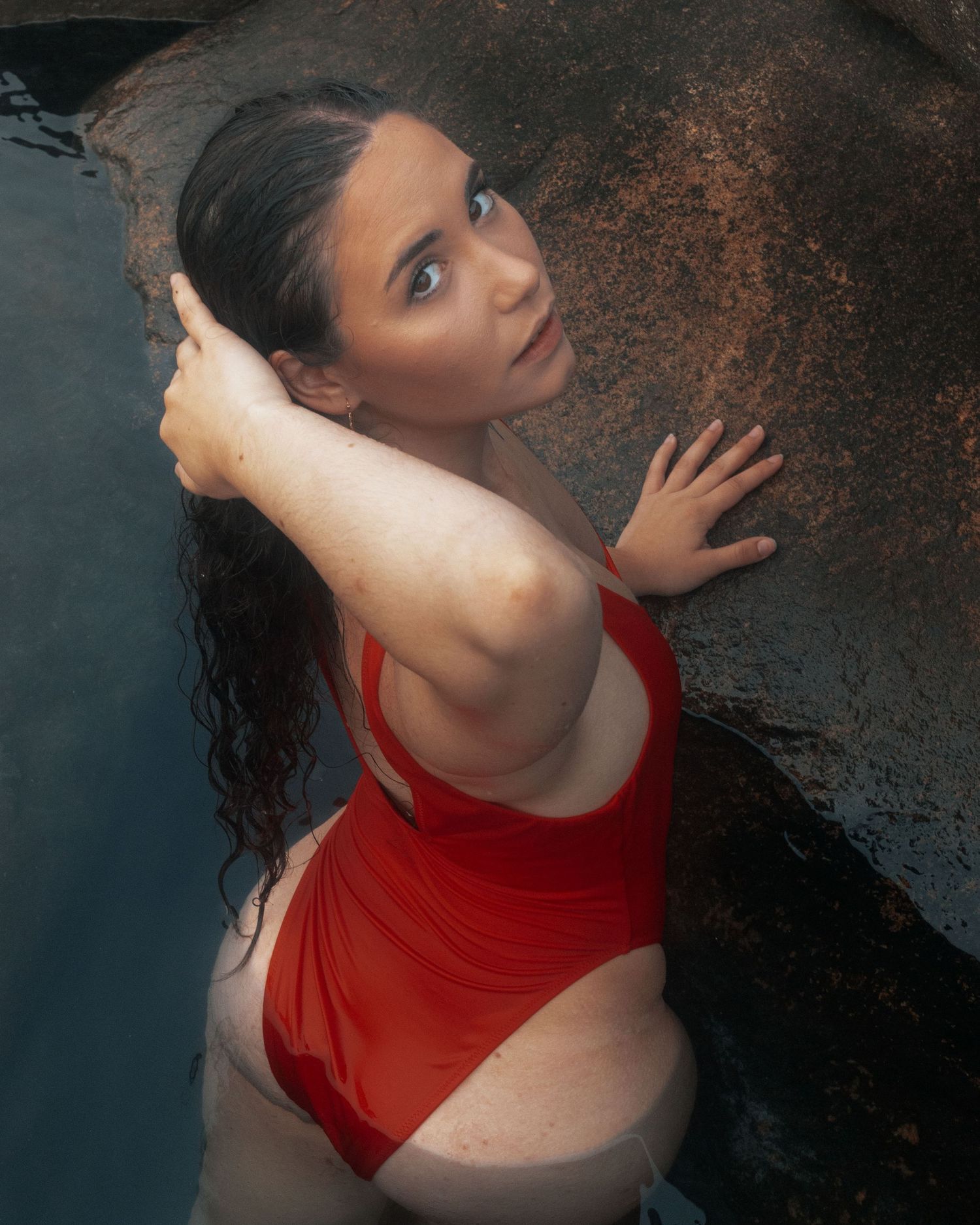 Artistic portrait series featuring a red swimsuit against a dark textured background.