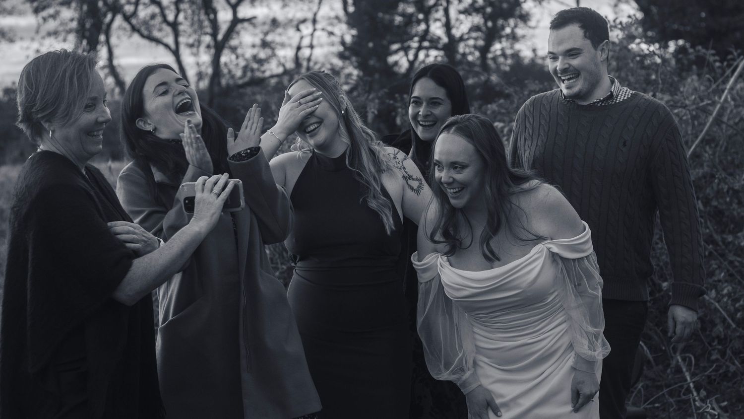 Wedding celebration with guests dancing and enjoying festivities in black and white.