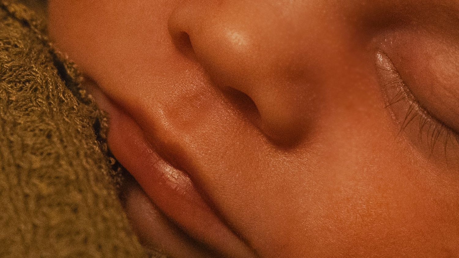 A macro close-up photograph of a person's mouth and lips in warm lighting.