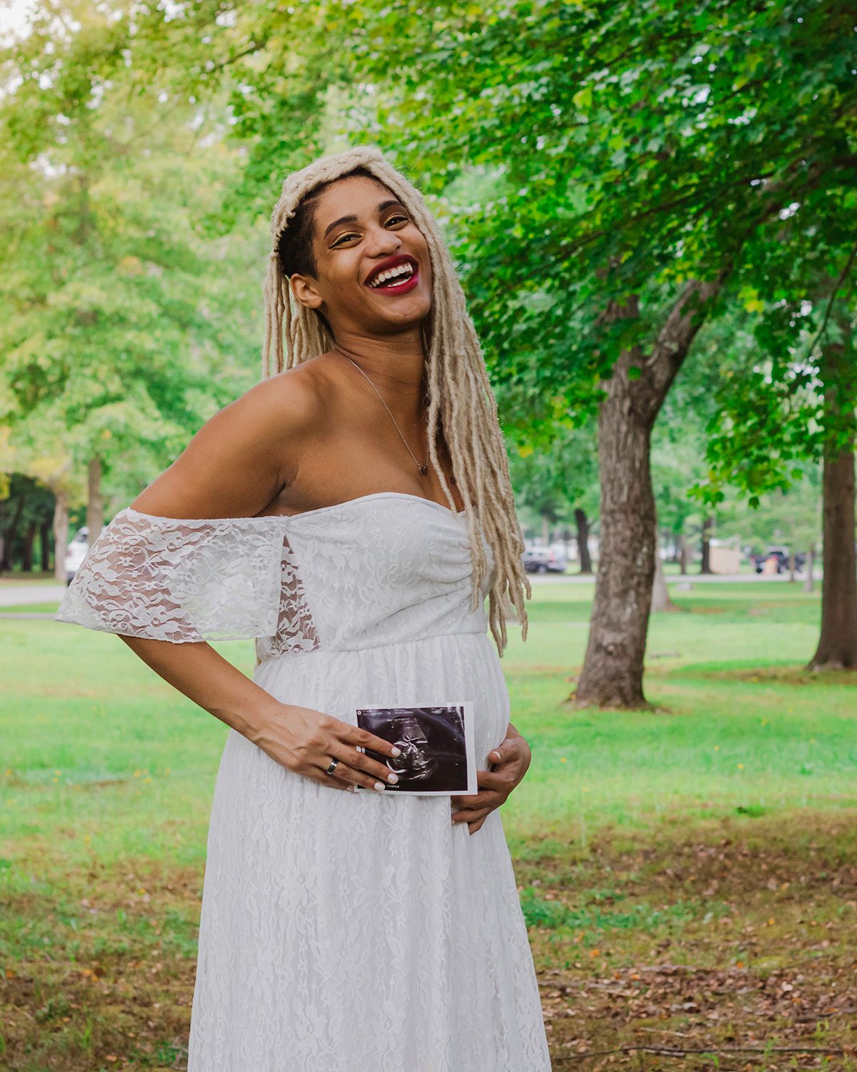 Maternity photoshoot in a lush green slater park, pawtucket, rhode island setting with a white lace dress.