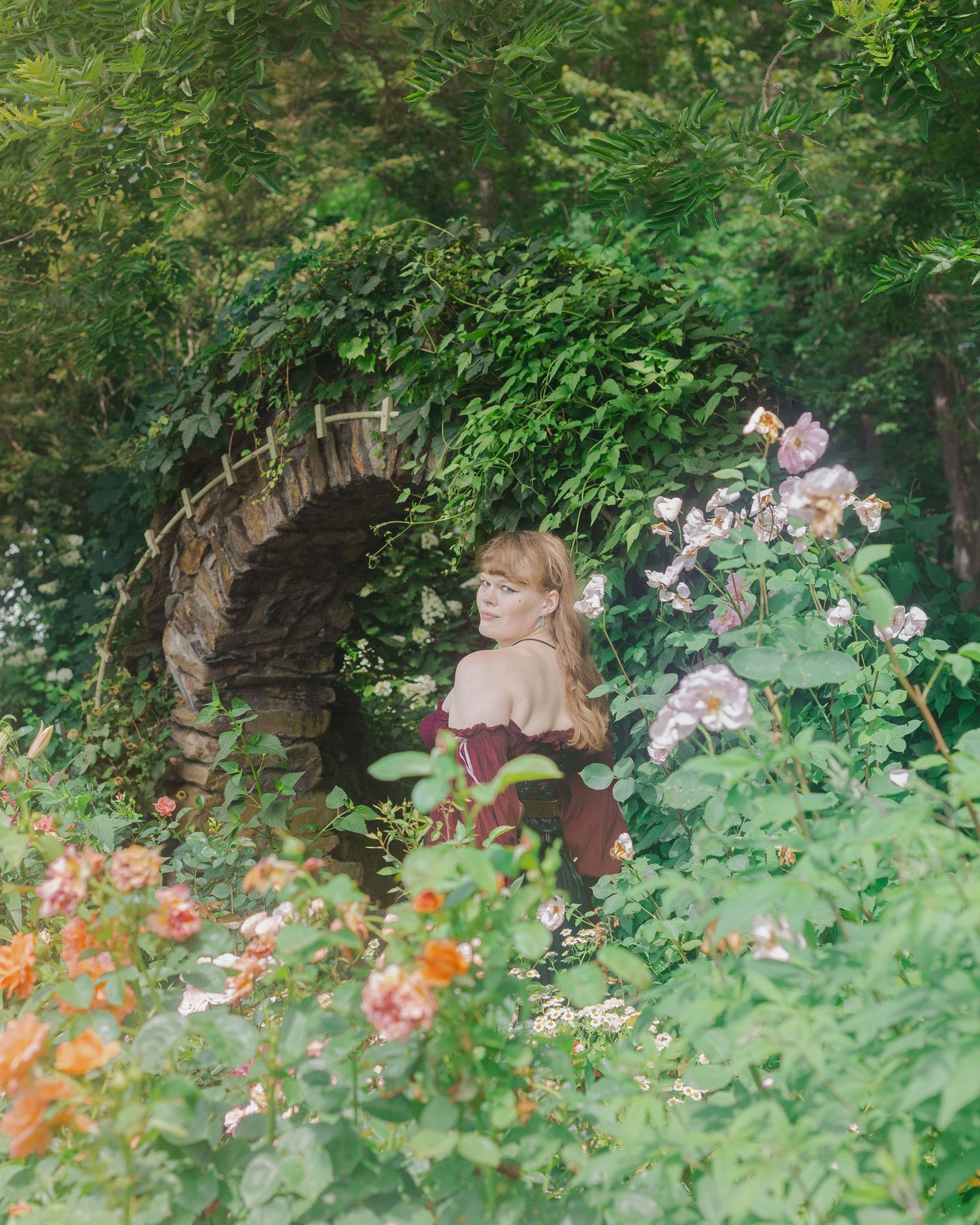 Garden scene with vibrant orange and pink flowers growing near a stone archway.