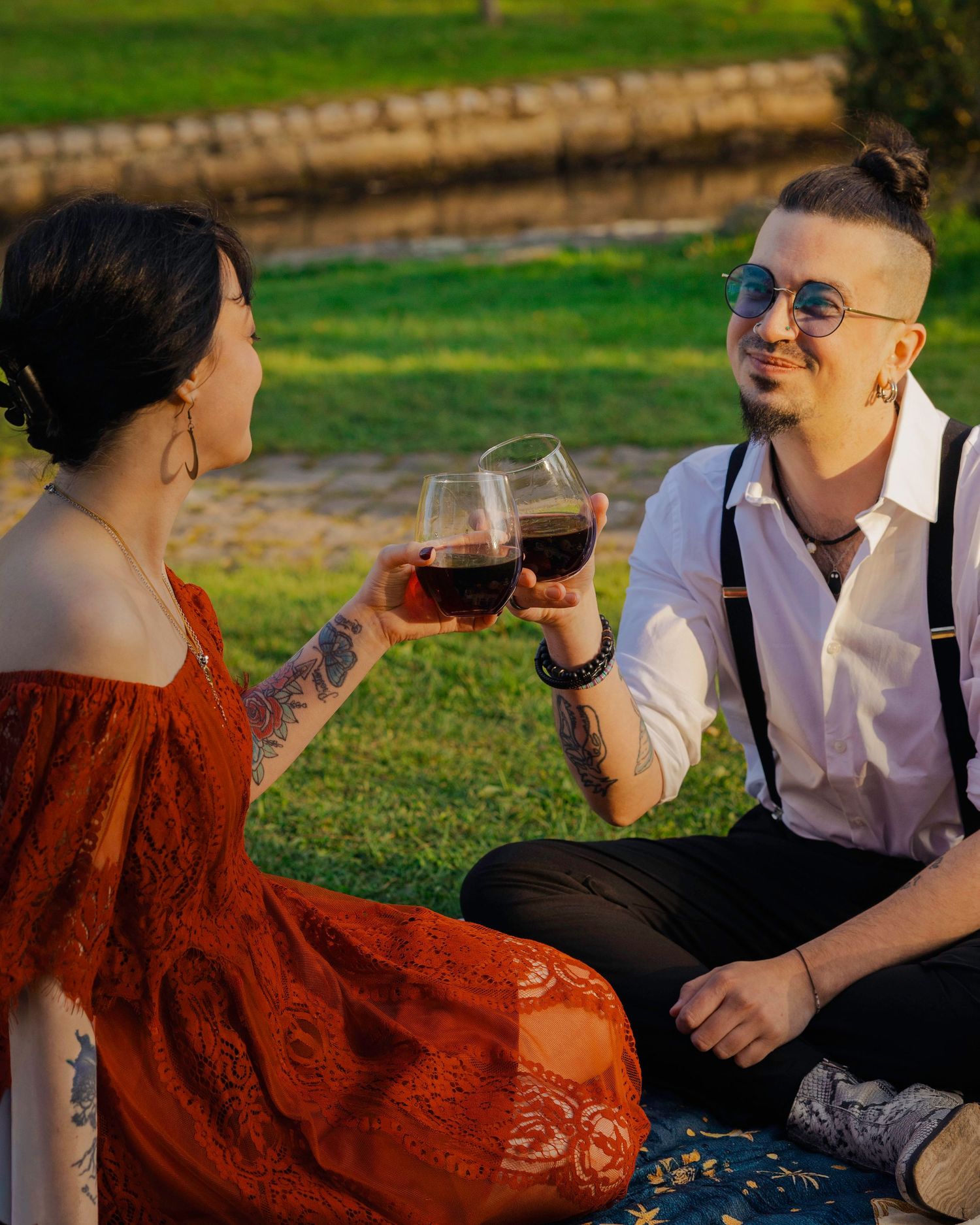 Couple toasting with red wine glasses during an outdoor picnic on a sunny day.