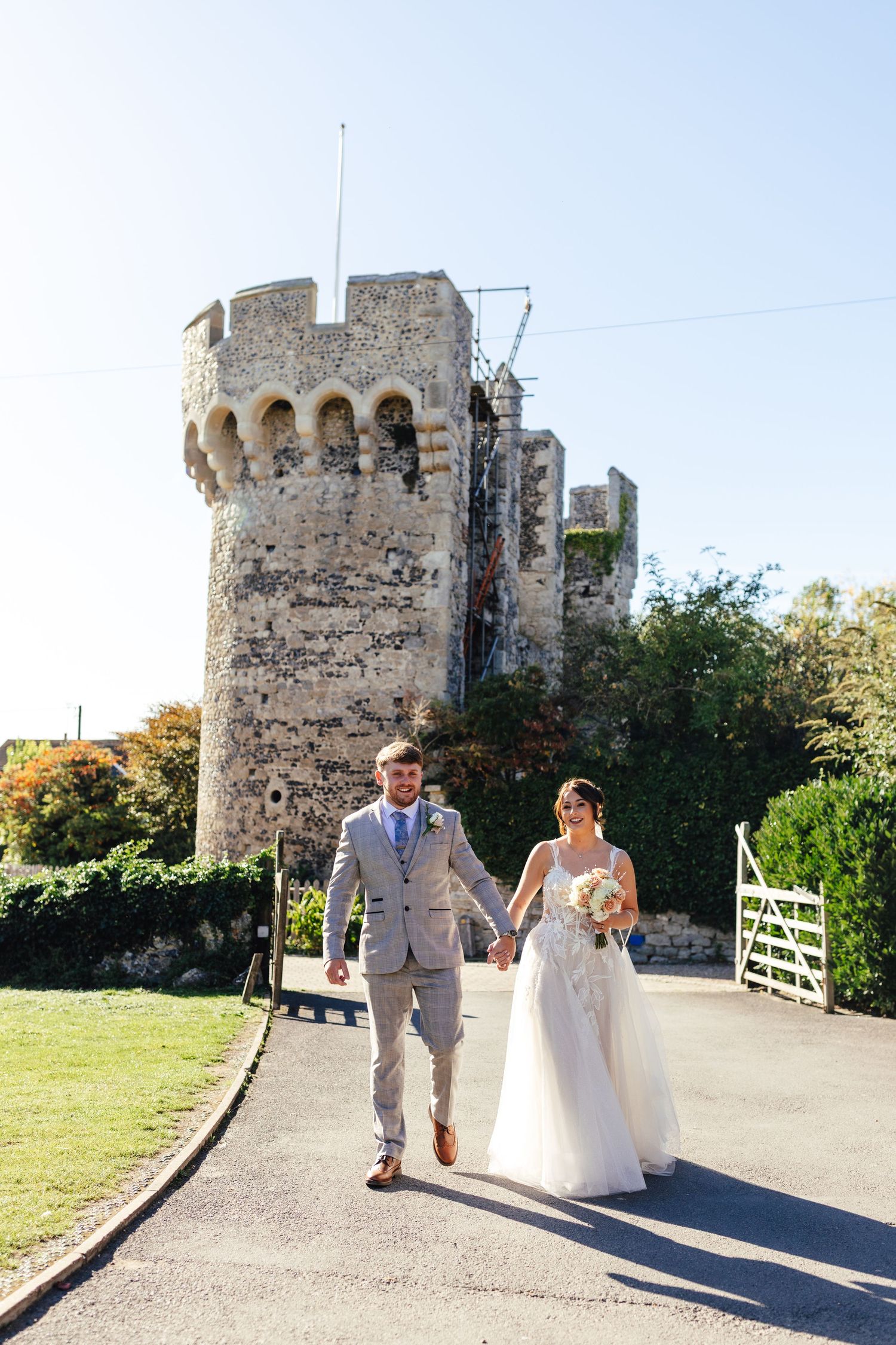 Couple walking by Cooling Castle Barn Kent, relaxed outdoor barn wedding photography
