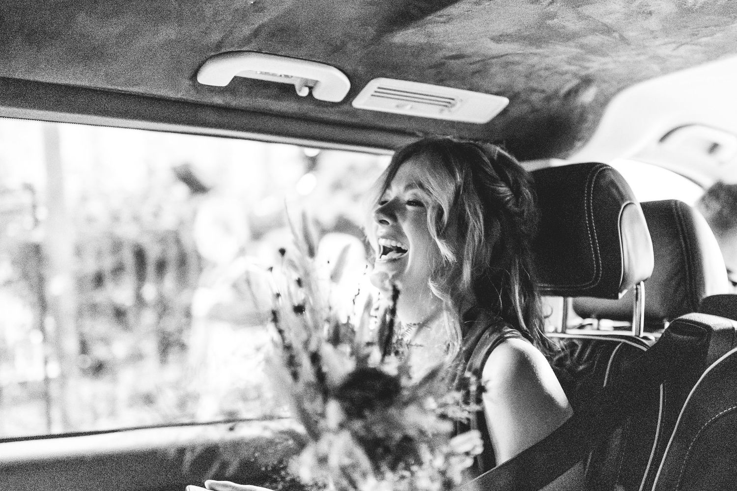 Bridesmaid in wedding car laughing in Nottingham, candid East Midlands wedding photography