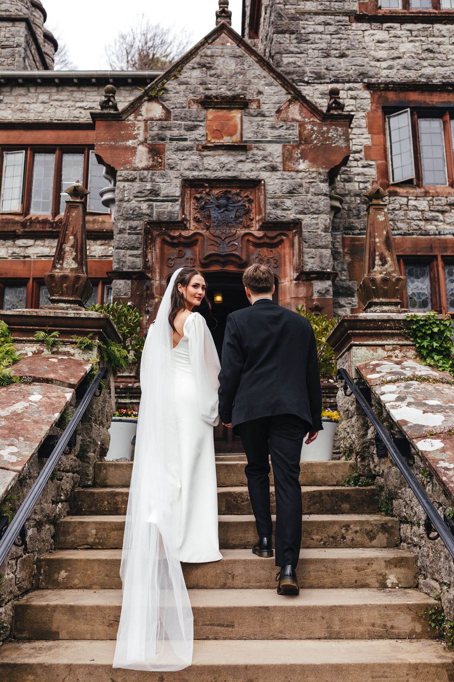 Bride and groom walking up steps at Netherwood Hotel and Spa, Lake District wedding photography