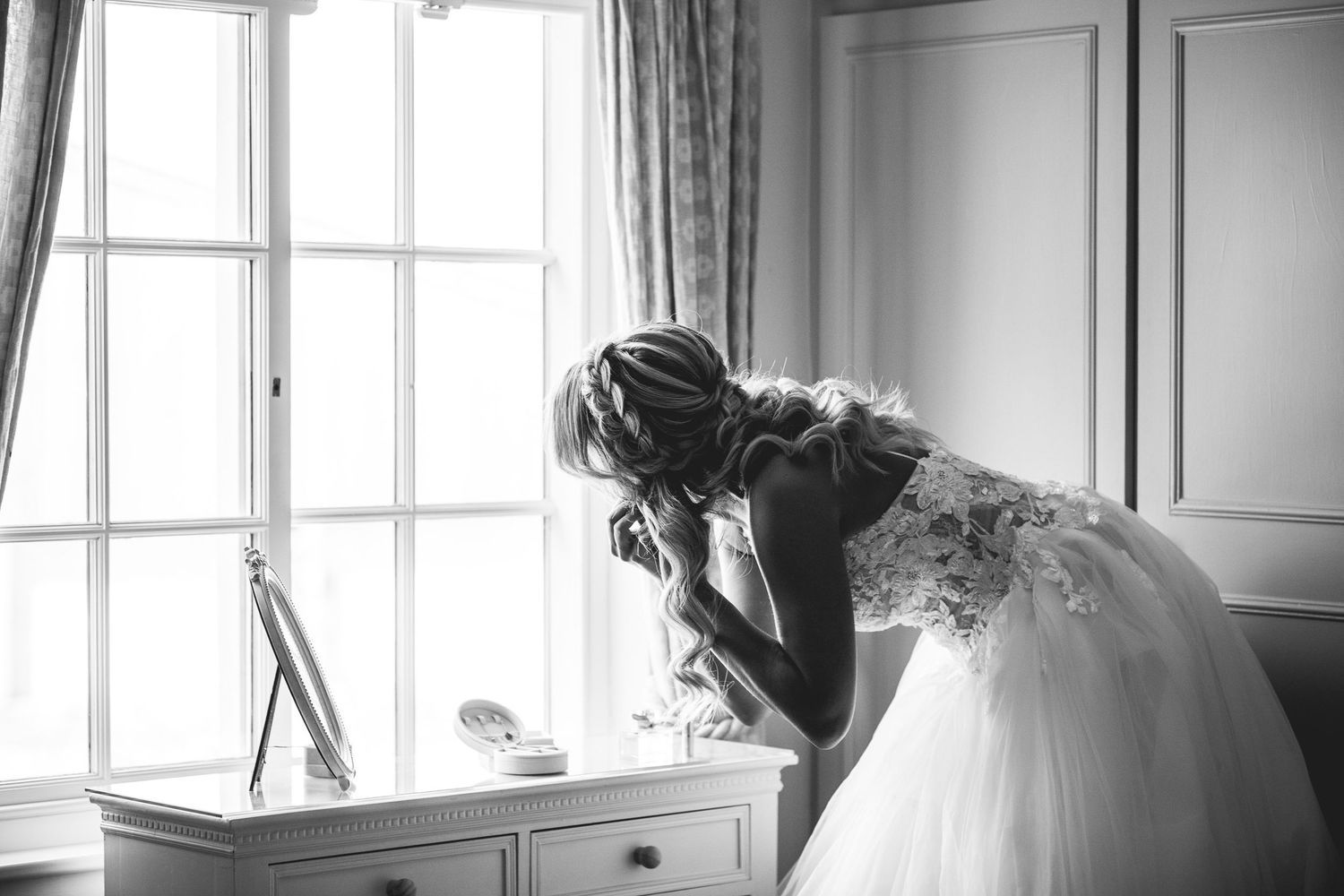 The Normans wedding photography York, bridal prep by window in elegant barn venue, natural documentary style