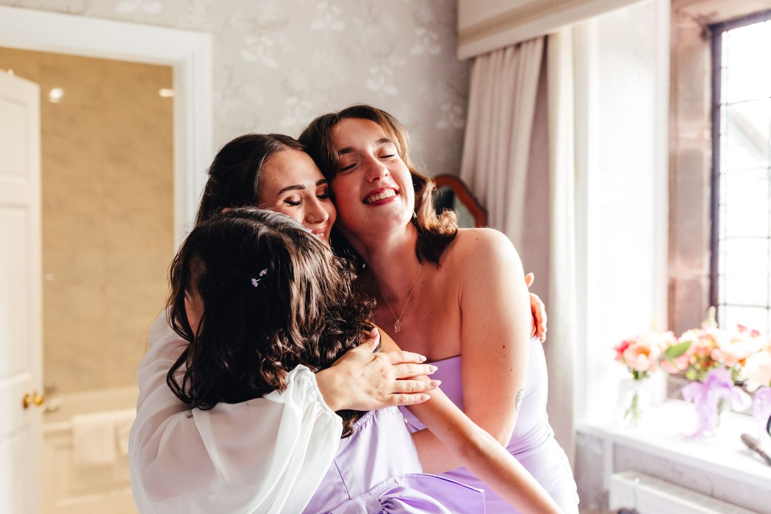 Bridesmaids hugging bride at Netherwood Hotel and Spa, Lake District spring wedding photography