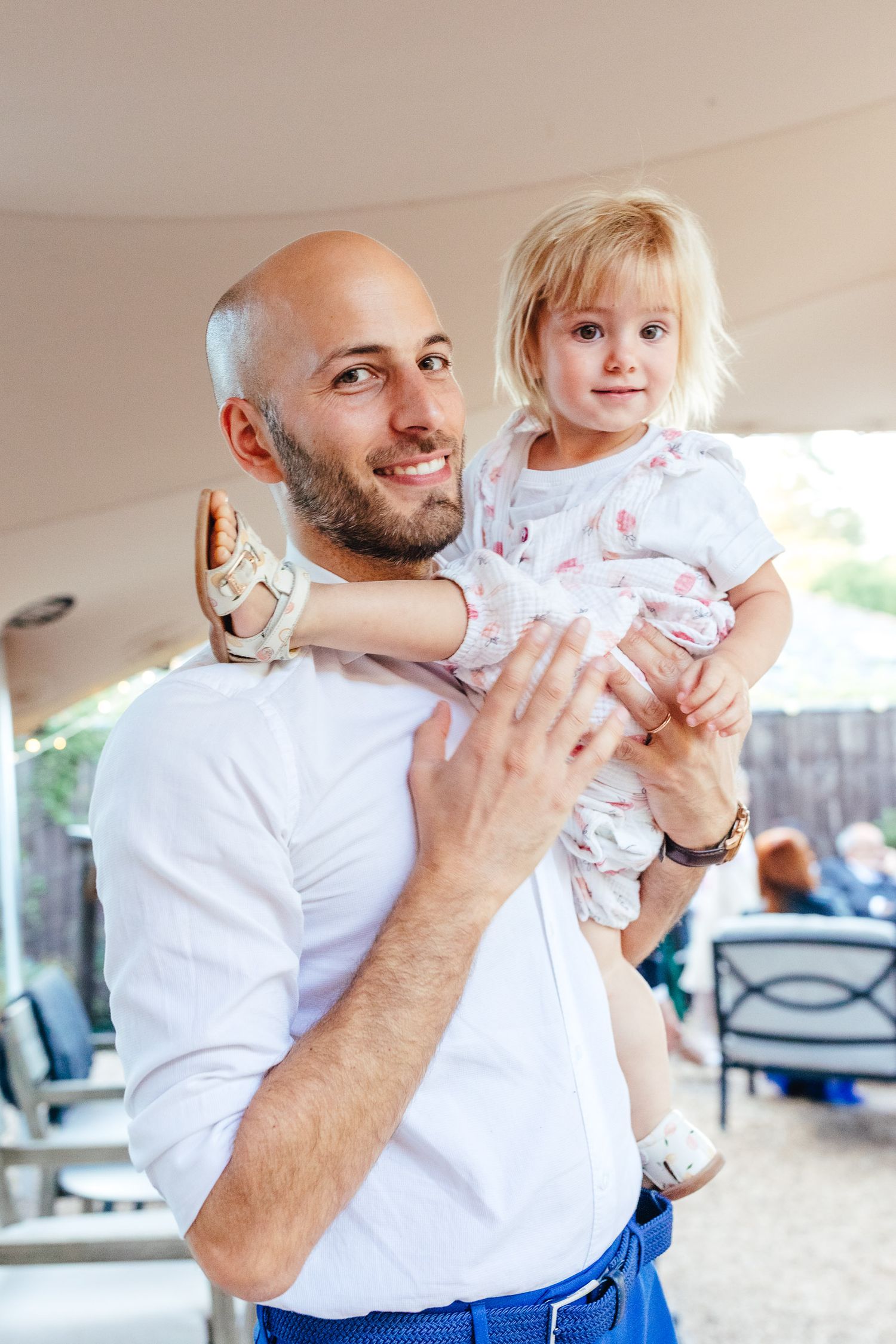 Father holding toddler during relaxed Derbyshire wedding reception, candid documentary wedding photography