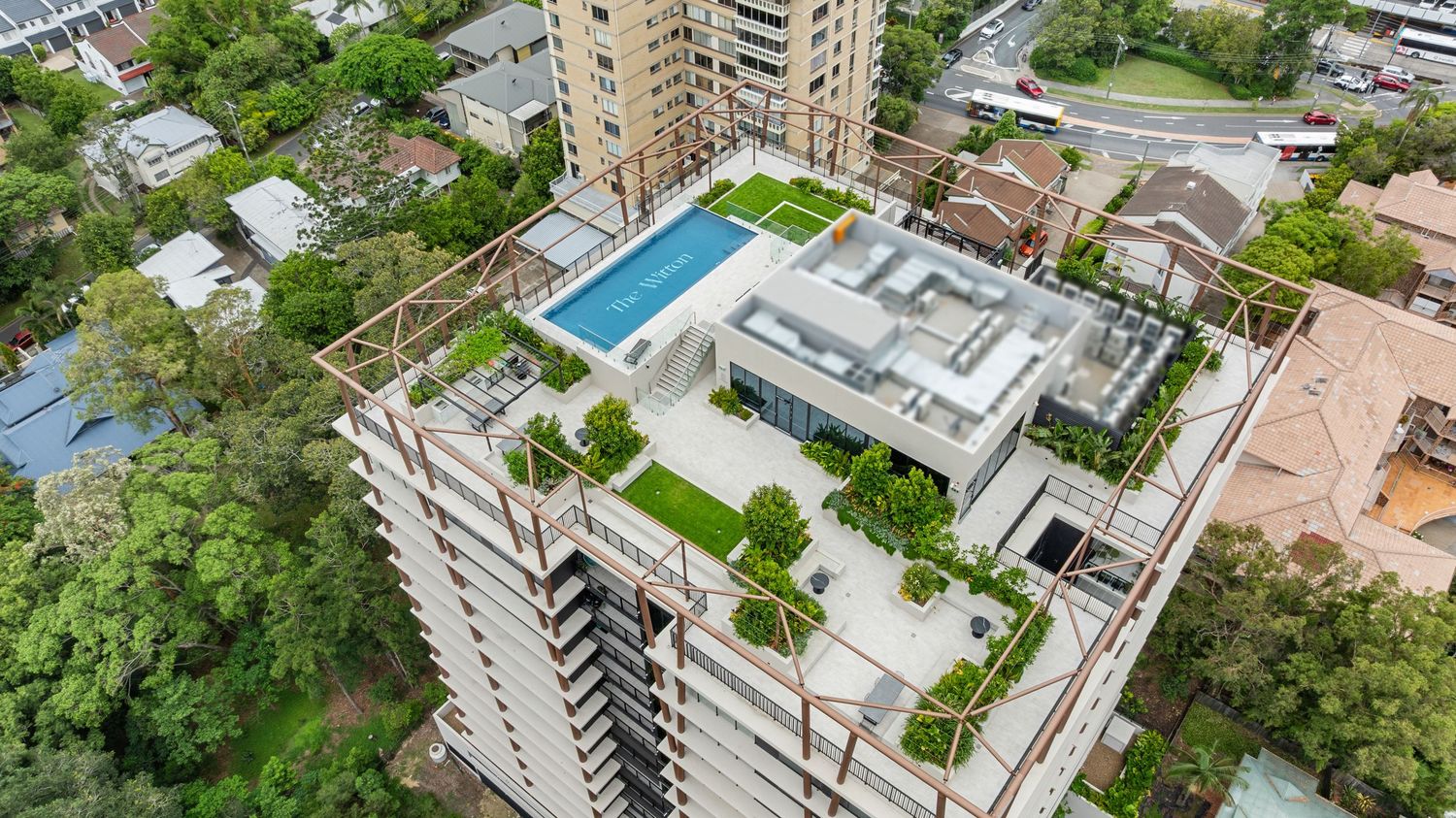 Aerial view of urban residential buildings surrounded by lush greenery and parking areas.