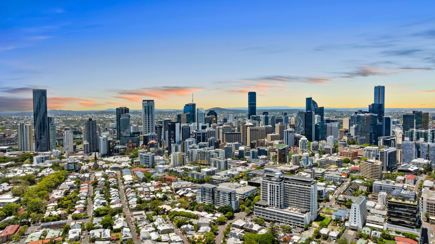 Wide aerial panorama of Brisbane city showing dense urban development and river winding through downtown.