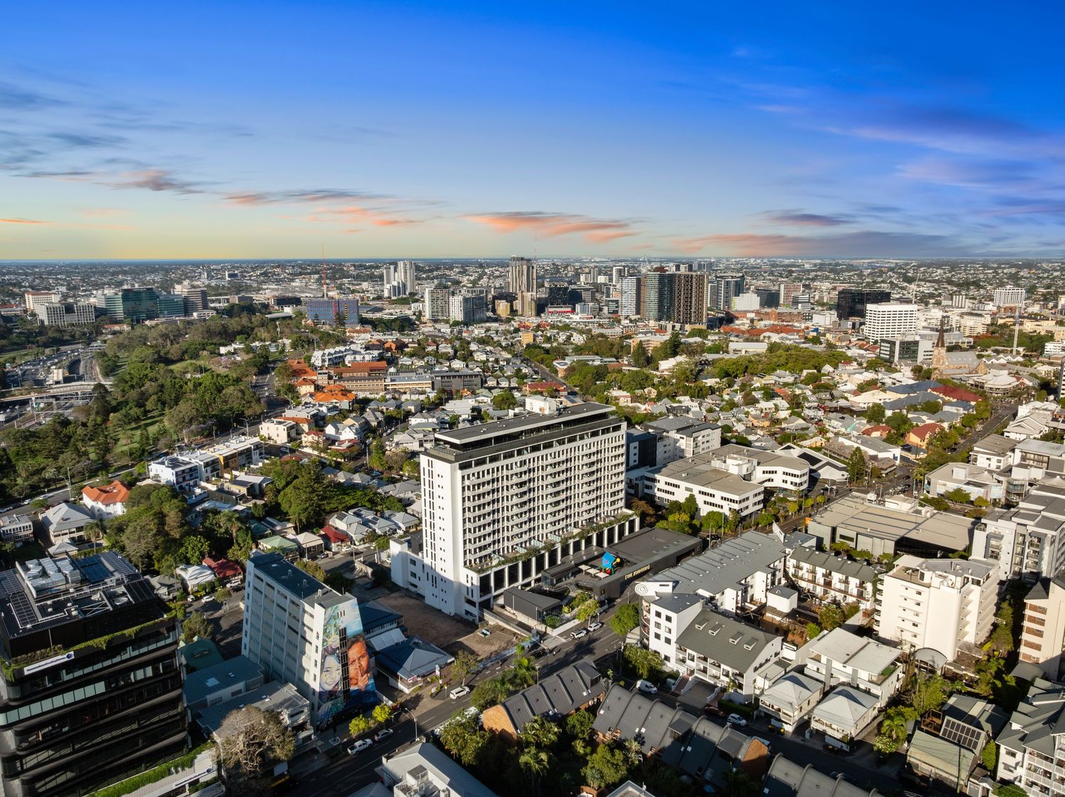 Panoramic cityscape view showing urban development and residential buildings against blue sky.
