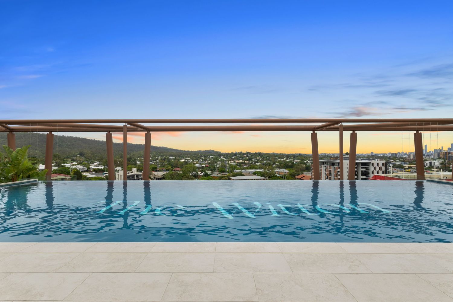 Panoramic waterfront view with wooden railings against blue sky and calm waters.